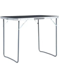 Petite table de camping pliante en aluminium et MDF 80 x 60 cm devant une tente
