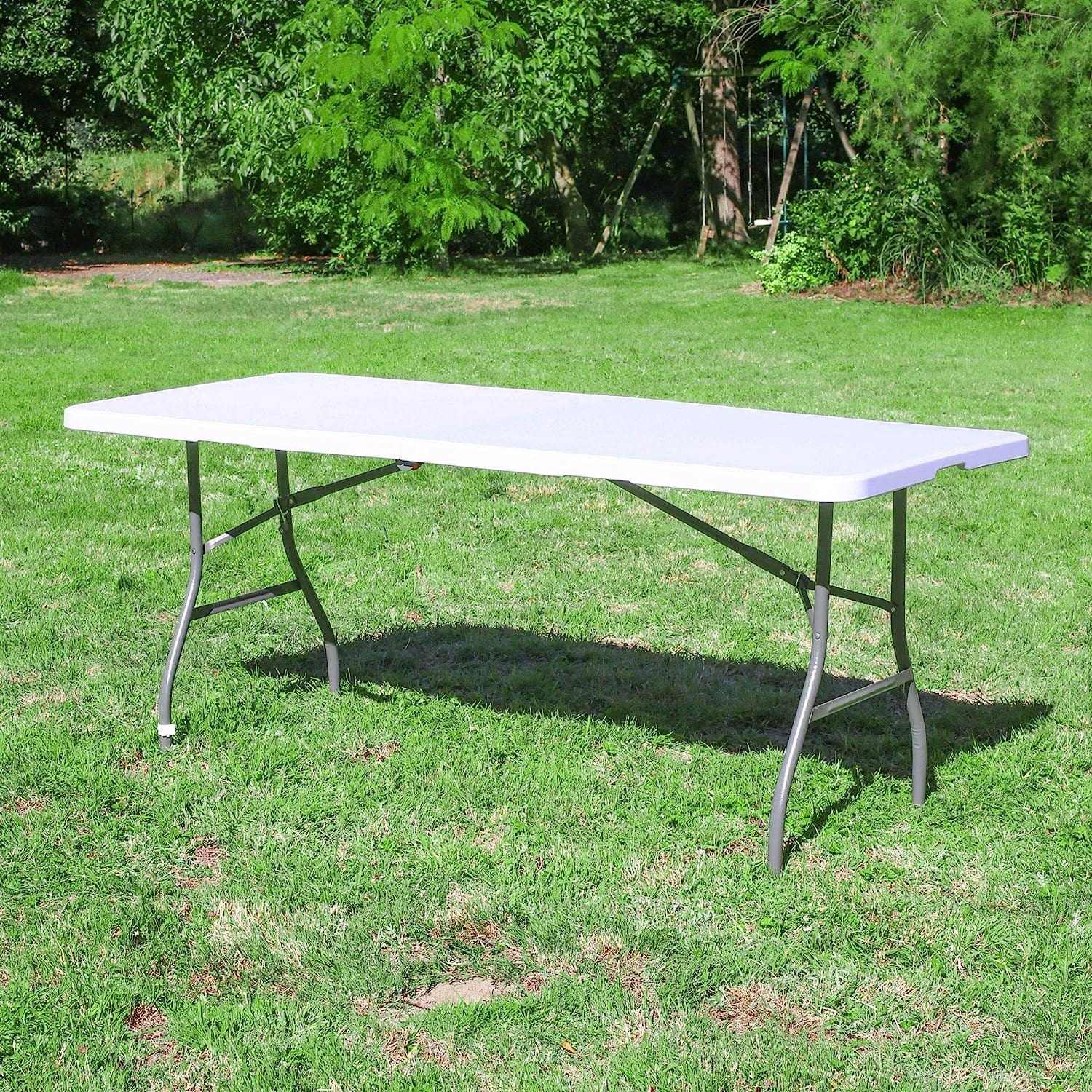 Table pliante blanche d'extérieur de 183 cm installée dans un jardin